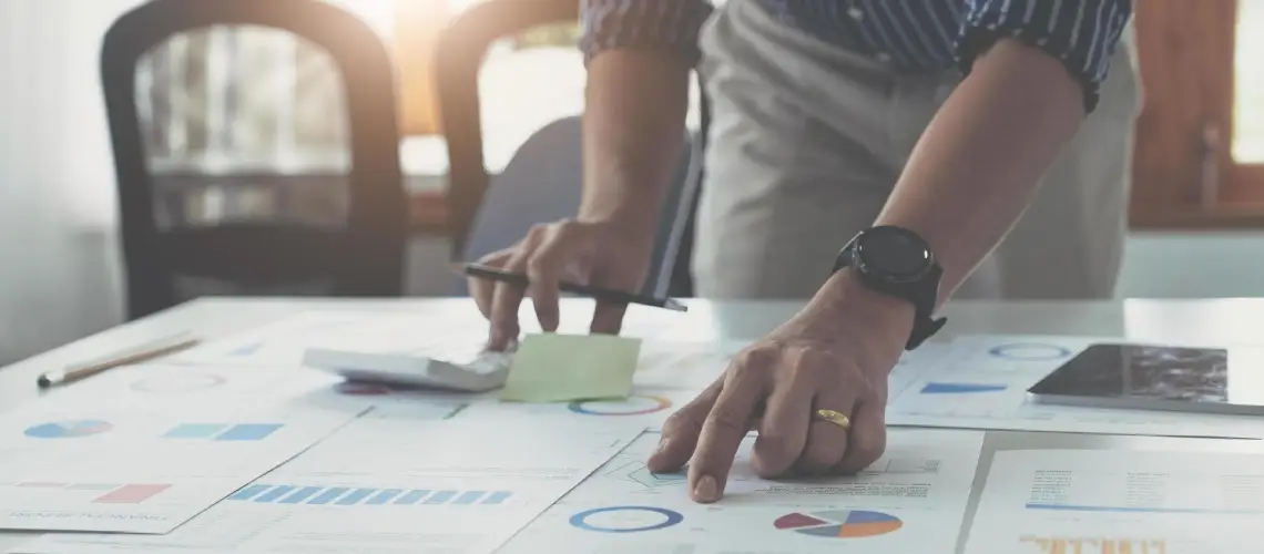 A Canberra-based business owner reviewing valuation documents with a calculator and charts